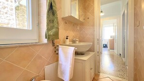 A bathroom with a white sink, a towel hanging on the wall, and a window.