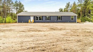 A single-story building with a dark exterior, a flat roof, and a door with a small porch area. - Four-season retreat with fireplace, firepit, grill, WiFi & central AC (Thompsonville)