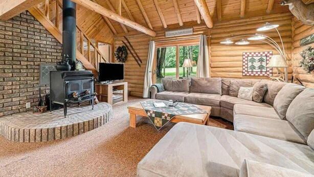 Interieur van een blokhut met een open haard, een bank, een televisie en een decoratie van een hertenkop.