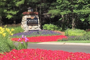 Señal de Crystal Mountain Resort & Spa rodeada de coloridas camas de flores y árboles.