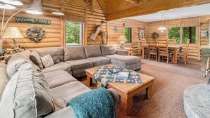 Een cabin interieur met een modulaire bank, een houten eettafel met stoelen, een gewatteelde salontafel en een welkomstbord.