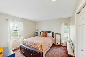 A bedroom with a bed, a desk, and a wardrobe. - Cottage on the canal to Burt Lake with large patio and space for boat (Indian River)
