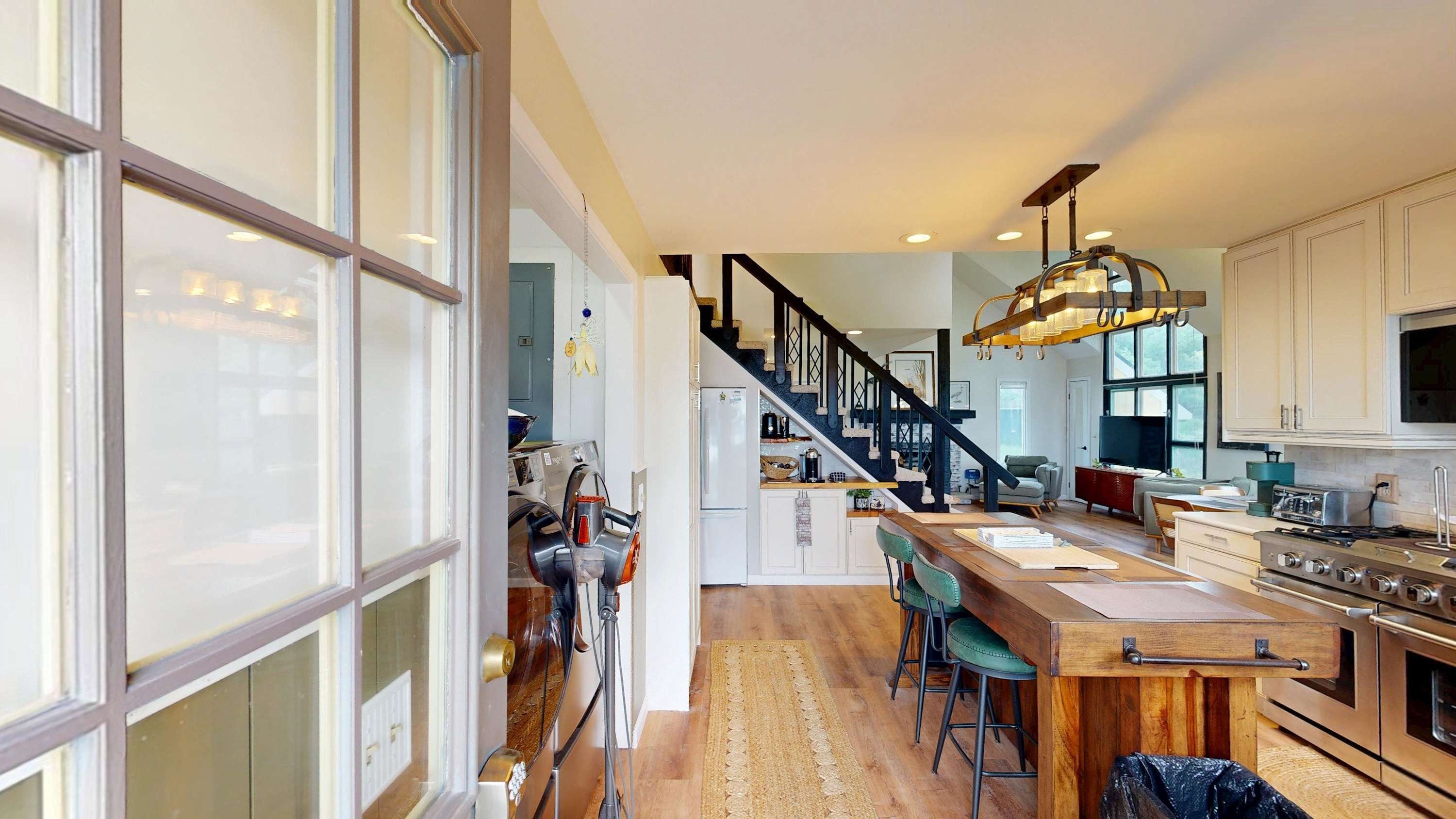 Una cocina moderna con una isla de madera, electrodomésticos de acero inoxidable y una escalera que conduce a una zona de altillo.