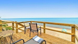 Une terrasse en bois avec deux chaises et une table, donnant sur une plage.