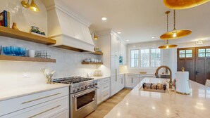 A modern kitchen with white cabinetry, a central island, stainless steel appliances, and pendant lighting. - Brand New Luxurious Home, w/ Fire pit, Gas Grill, near Lakes & Trails! (Glen Arbor)