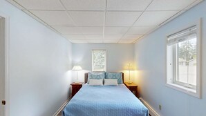 Une chambre à coucher avec un lit, deux tables de chevet avec des lampes, une fenêtre et une porte.