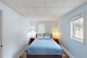 A bedroom with a bed, two bedside tables with lamps, a window, and a door. - Dreamy Coastal Cottage W/ Free WiFi, Full Kitchen, & Large Deck - Walk to Town (Harbor Springs)