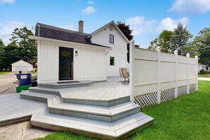 A single-story house with a front porch and a garage. - Dreamy Coastal Cottage W/ Free Wi-Fi, Full Kitchen, & Large Deck - Walk to Town (Harbor Springs)