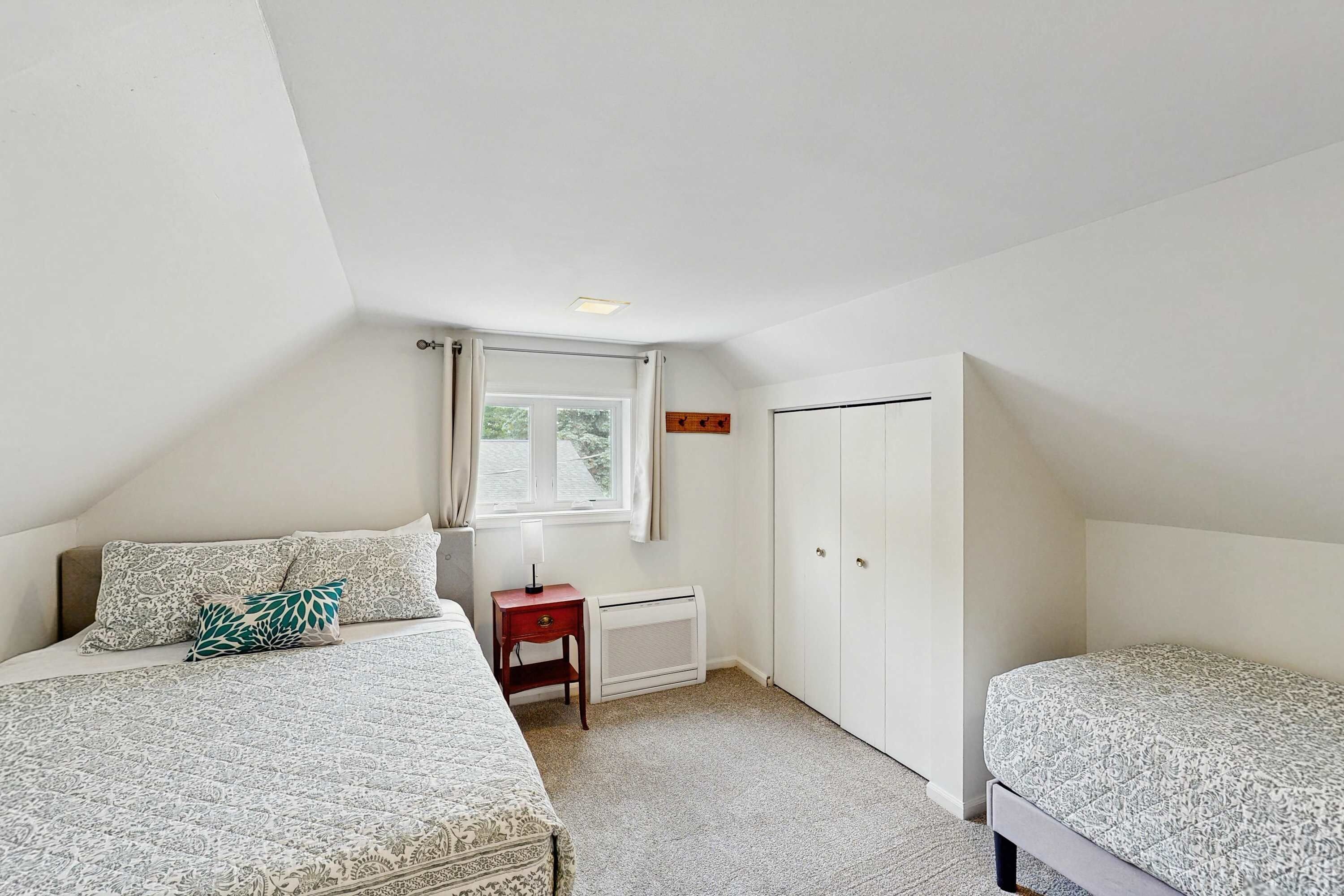 Een slaapkamer met twee bedden, een raam, een radiator en een deur.