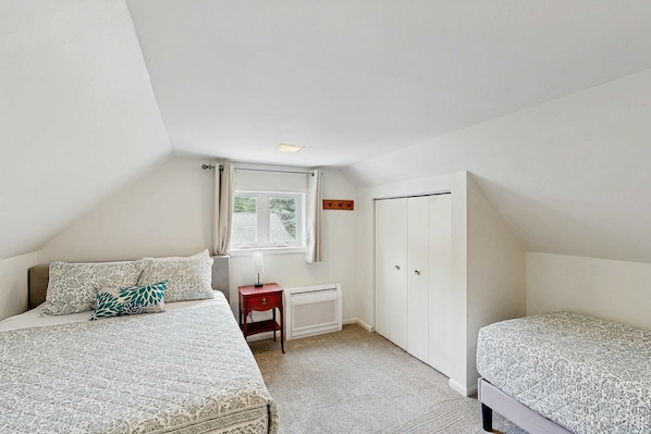 A bedroom with two beds, a window, a radiator, and a door. - Dreamy Coastal Cottage W/ Free Wi-Fi, Full Kitchen, & Large Deck - Walk to Town (Harbor Springs)