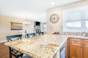 A kitchen with a granite countertop, wooden cabinets, a built-in oven, and a dining area with chairs.