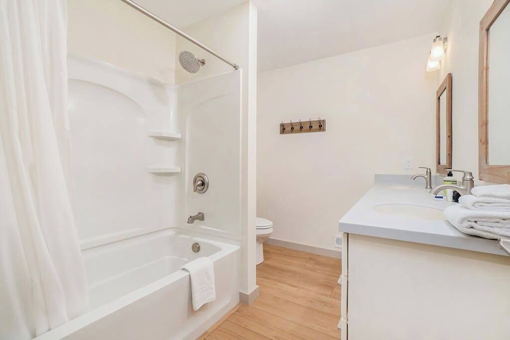 A bathroom with a bathtub, a toilet, a sink with a mirror, and a towel rack.
