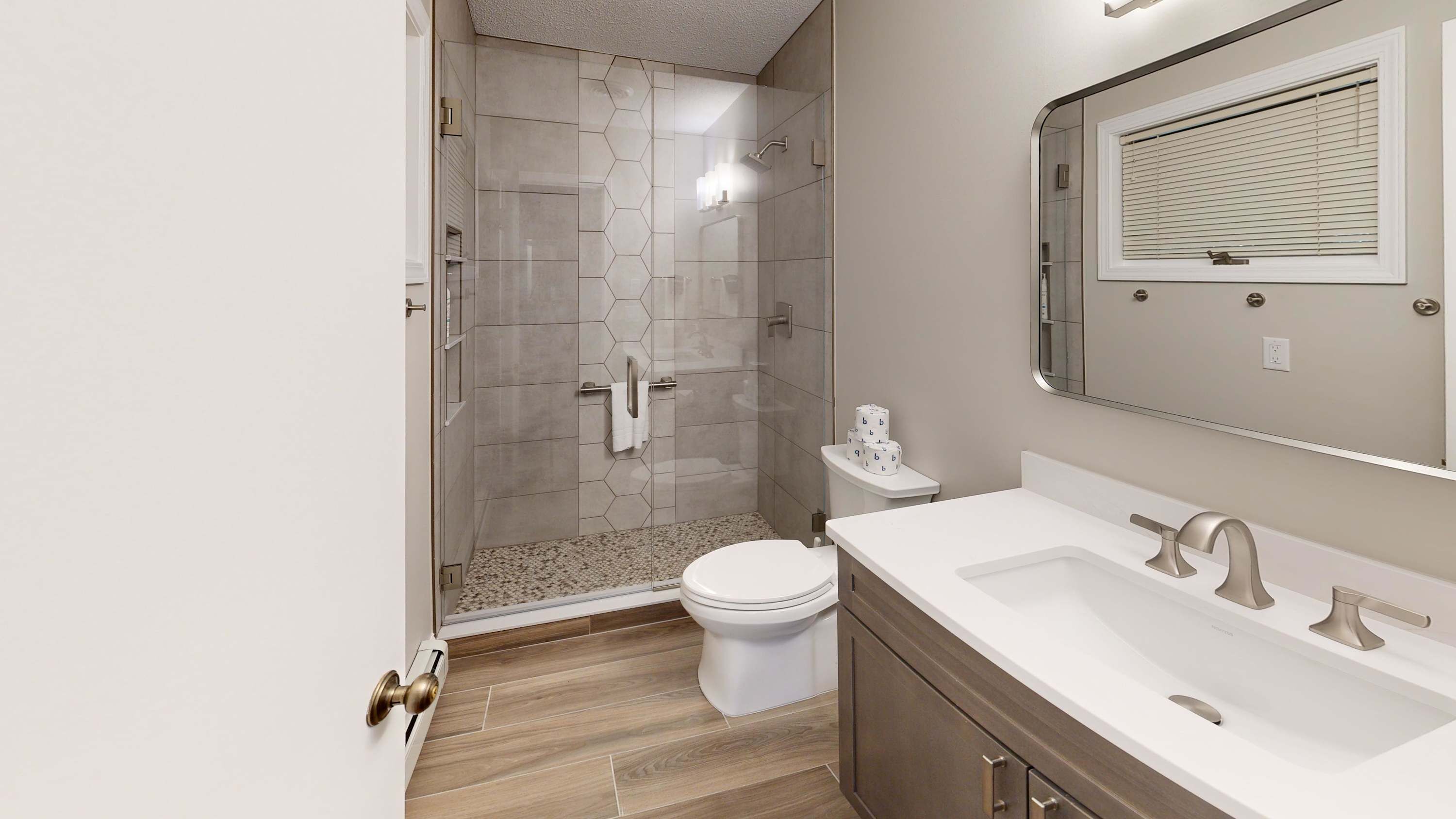 A modern bathroom with a shower, toilet, and vanity.