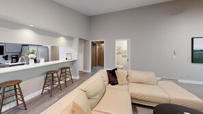 A modern apartment with a kitchenette, a living area with a sofa, and a hallway leading to another room. - Secluded home with three kitchens, vaulted ceilings, washer/dryer, & patios (Glen Arbor)