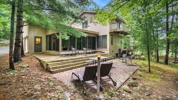 Une maison moderne dotée d’une terrasse, d’un espace salon extérieur et d’un escalier menant à un balcon.