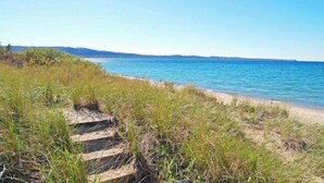A coastal path leading to a beach with clear skies. - Tasteful Glen Arbor condo with beautiful Lake Michigan views, deck & fireplaces (Glen Arbor)