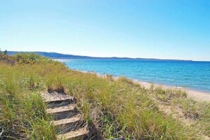 A coastal path leading to a beach with clear skies.
