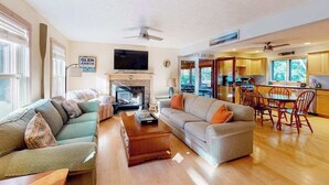 Ein Wohnzimmer mit Kamin, Fernseher und Essbereich mit Holzmöbeln.