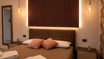 Een moderne slaapkamer met een groot bed, twee nachtkastjes, een spiegel en een wandlamp.