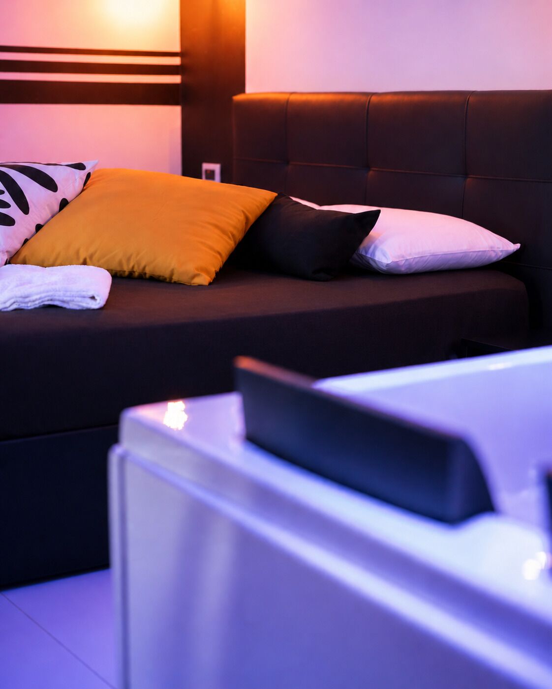 A bed with a headboard, pillows, and a white towel.