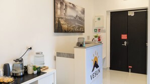 Un mostrador de recepción con un logotipo, una máquina de café, un dispensador de agua y un cuadro en la pared.