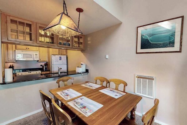A kitchen with wooden cabinets, a microwave, a stove, and a hanging light fixture.