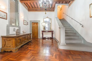 A grand hallway with a wooden floor, a staircase, a chandelier, and a large mirror. - Palazzo Simonetti - a noble elegance in the heart of Cortona (Cortona)