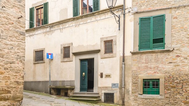 A stone building with a green door, a small window with shutters, and a number '2' sign. - Palazzo Simonetti - a noble elegance in the heart of Cortona (Cortona)