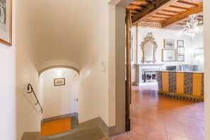 A staircase leading to a living area with a fireplace, a patterned sofa, and a chandelier. - Palazzo Simonetti - a noble elegance in the heart of Cortona (Cortona)