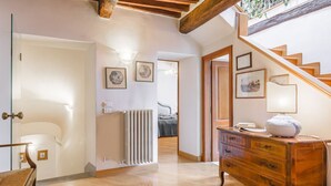 A spacious hallway with a wooden staircase, a radiator, and a dresser with a lamp. - Palazzo Simonetti - a noble elegance in the heart of Cortona (Cortona)