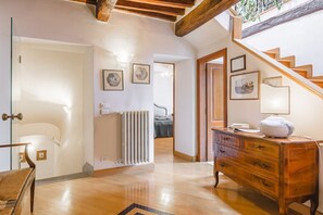 A spacious hallway with a wooden staircase, a radiator, and a dresser with a lamp. - Palazzo Simonetti - a noble elegance in the heart of Cortona (Cortona)