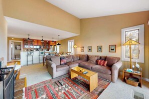 A spacious living area with a sofa set, a coffee table, and a patterned rug.
