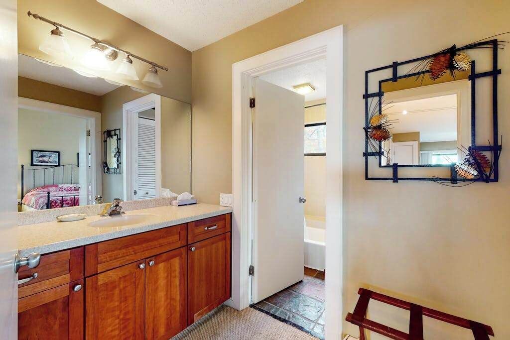 A bathroom with wooden cabinets, a sink, a mirror, and a decorative wall piece.