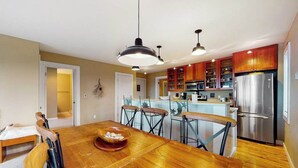 Una cucina moderna con zona pranzo, elettrodomestici in acciaio inossidabile e tavolo da pranzo in legno.
