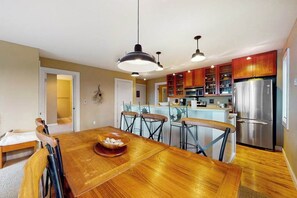 A modern kitchen with a dining area, stainless steel appliances, and a wooden dining table.