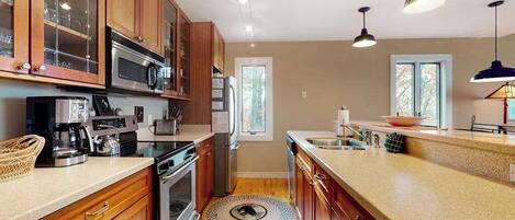 A kitchen with wooden cabinets, stainless steel appliances, and pendant lighting.