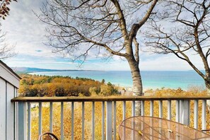 A balcony with a view of the sea, a tree, and a chair.