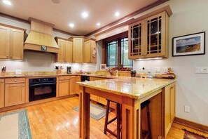 Una cocina con armarios de madera, horno empotrado, encimera de granito y ventana con vistas.