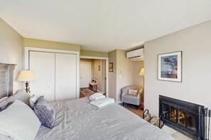 Une chambre à coucher comprenant un lit, une cheminée, un fauteuil et une porte donnant sur une autre pièce.