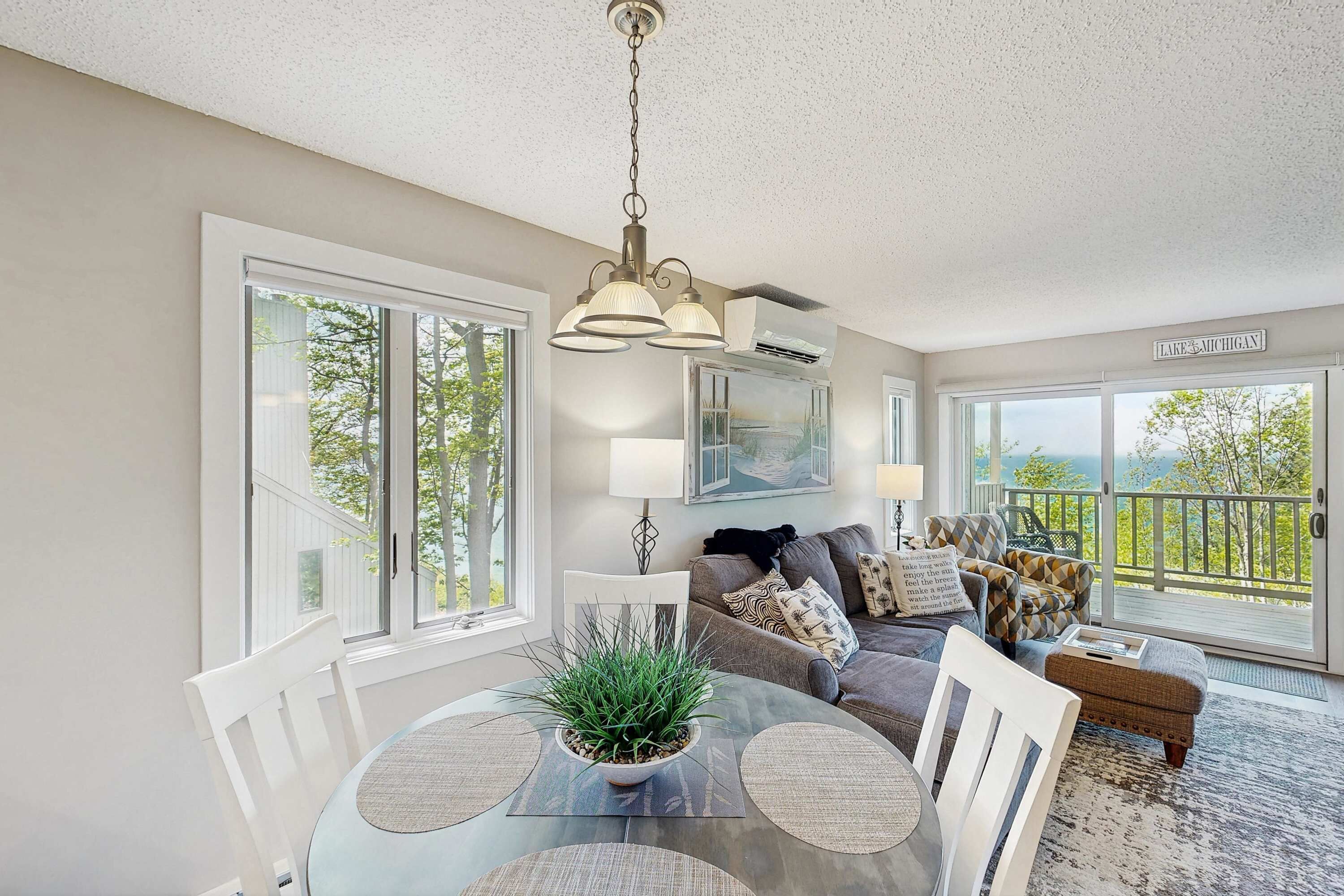 A spacious living room with a dining area, large windows, and a balcony with a view.