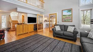 Ein großzügiger Wohnbereich mit grauem Sofa, einer Holzeinrichtungsanlage und einem großen Fenster mit Landschaftsblick.