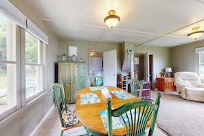 Un comedor con una mesa de madera, sillas verdes y un armario con puertas de vidrio.