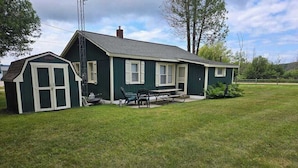 Ett hus med ett stort garage, en uteplats med bord och stolar samt en gräsyta.