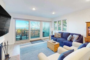 A living room with a sofa, coffee table, and a fireplace. - Beachfront condo in Glen Arbor with deck, fireplace, Lake Michigan views & W/D (Glen Arbor)