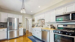 A modern kitchen with stainless steel appliances, white cabinetry, and a wooden floor. - Arcadia Retreat w/ private hot tub, gas grill, fire pit, near beach, Dogs- YES! (Arcadia)