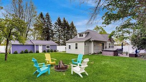 A backyard with a fire pit, three Adirondack chairs, and a house with a sloped roof. - Arcadia Retreat w/ private hot tub, gas grill, fire pit, near beach, Dogs- YES! (Arcadia)