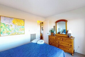 Un dormitorio con cama, cómoda, espejo y un cuadro en la pared.