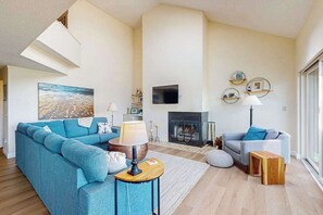 Una sala de estar moderna con un sofá, un televisor, una chimenea y un ventanal grande.