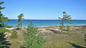 A coastal landscape with trees and a clear view of the sea. - Darling condo on Lake Michigan with washer/dryer, deck, lake views, fireplace (Glen Arbor)