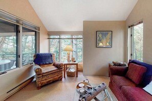 A cozy living room with a patterned sofa, a red couch, a small table, and a lamp.